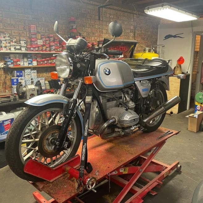 A BMW Motorcycle is Sitting on a Lift in a Garage — Coastal Automotive Services Long Jetty in Killarney Vale, NSW