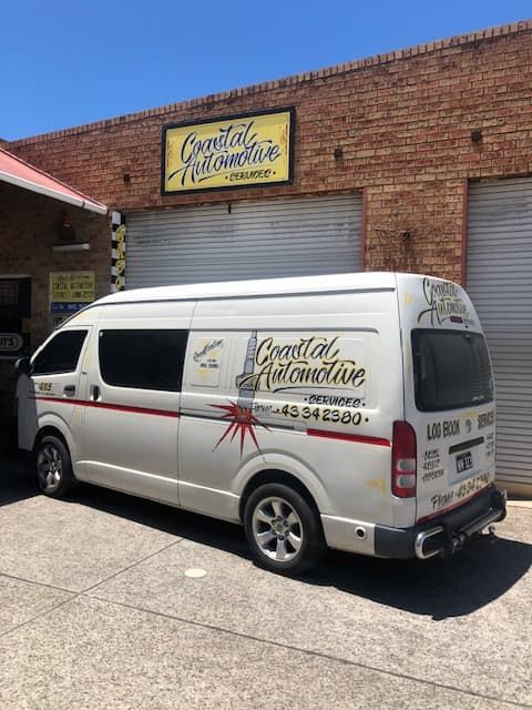 A White Van is Parked in Front of a Brick Building — Coastal Automotive Services Long Jetty in Long Jetty, NSW