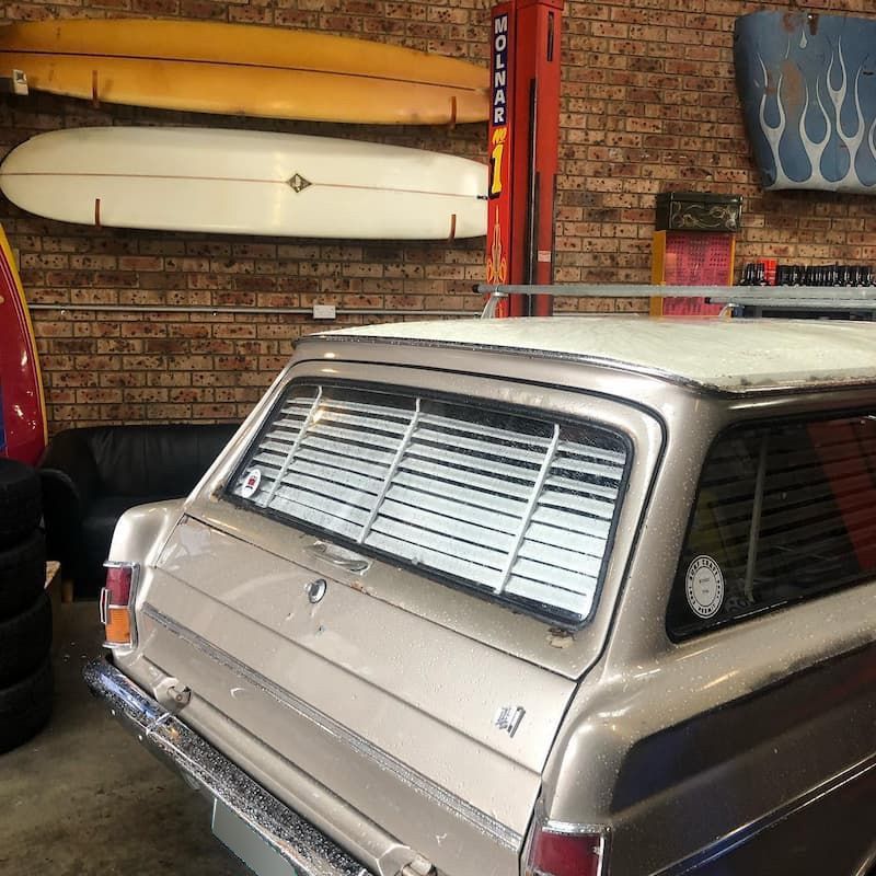 A Car is Parked in a Garage With Surfboards Hanging on the Wall — Coastal Automotive Services Long Jetty in Long Jetty, NSW