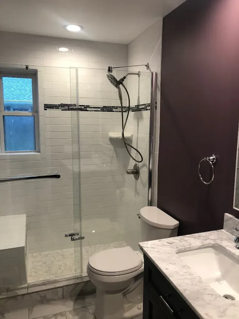 A bathroom with a toilet , sink , shower and window.