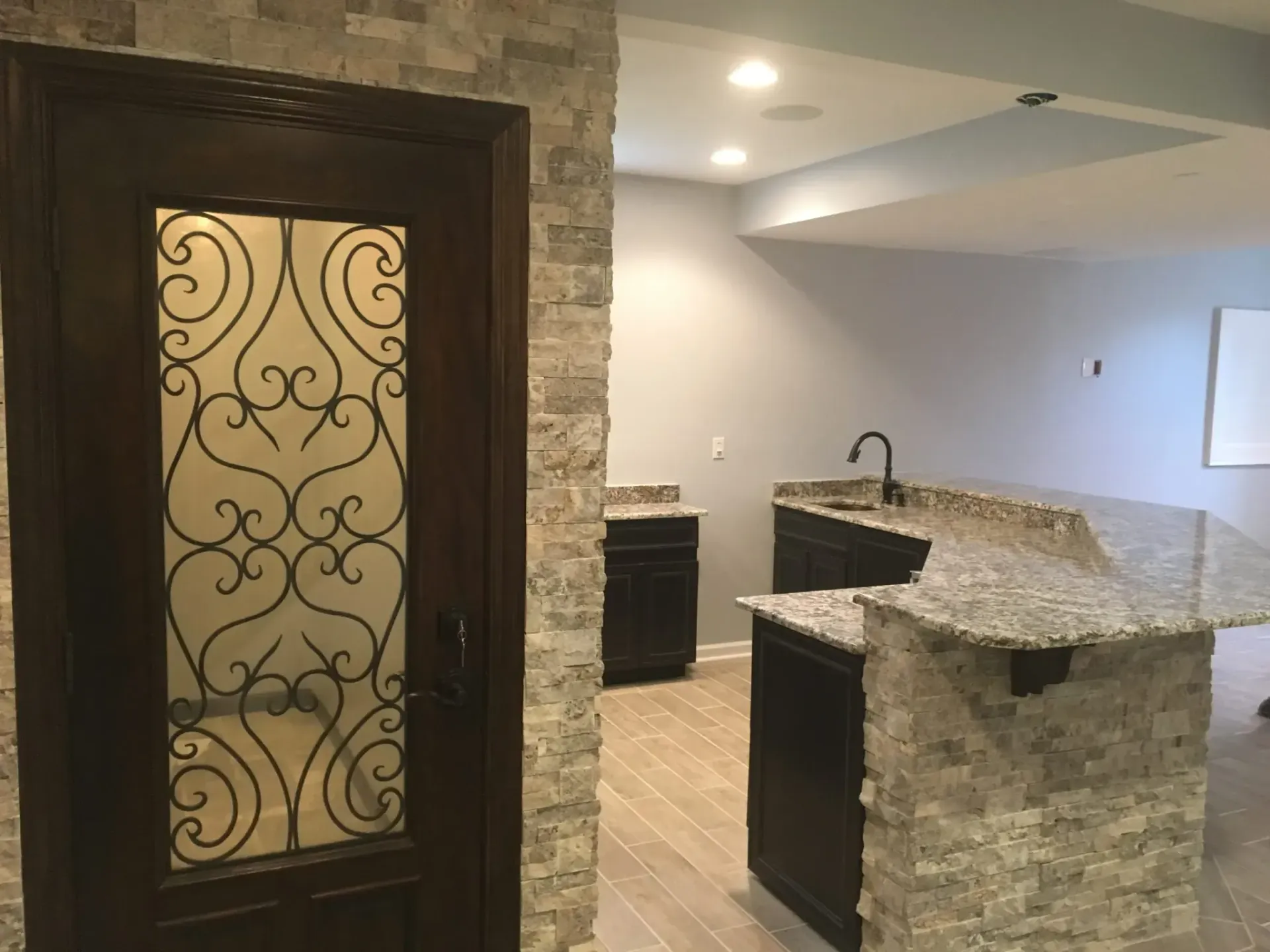 A kitchen with a wrought iron door and a granite counter top.