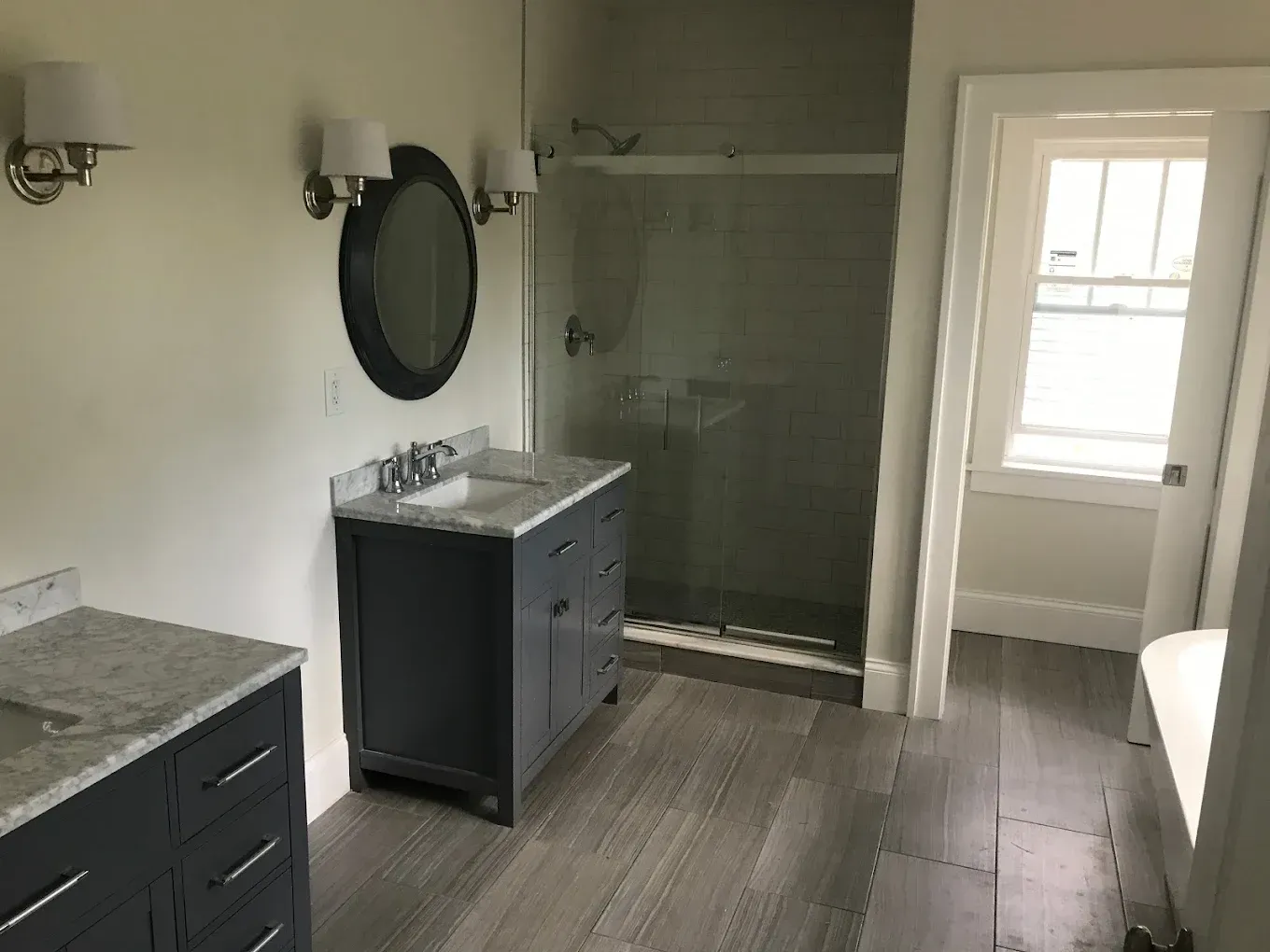 A bathroom with a sink , mirror and walk in shower.