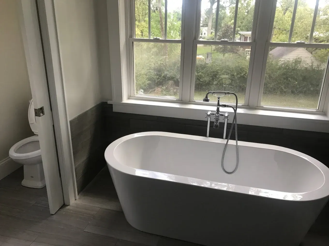 A bathroom with a bathtub , toilet and window.