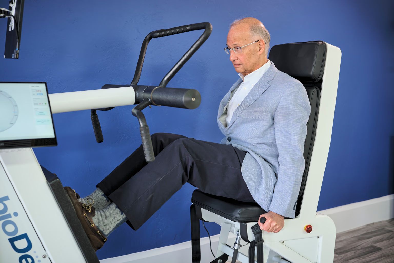 A man in a suit is sitting on a machine with his legs crossed.