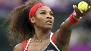 A woman is holding a tennis ball in her hand.