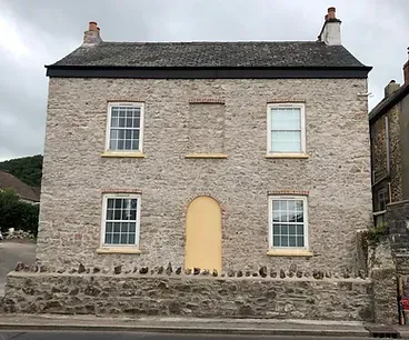 A large stone house with a yellow door and windows.