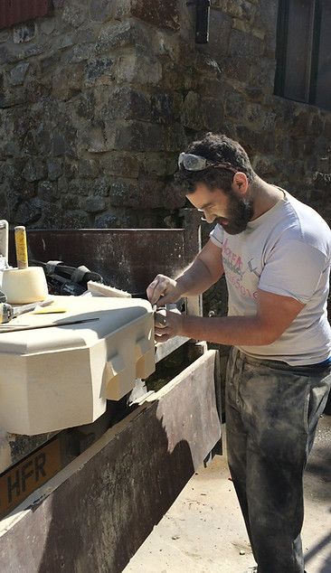 A man with a beard is working on a piece of wood.