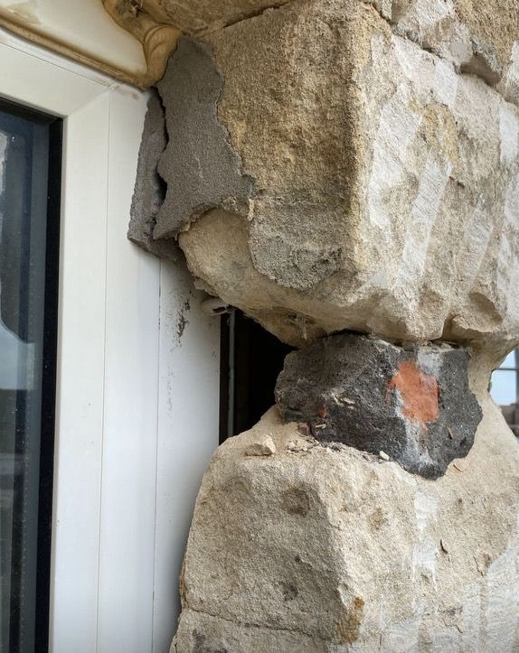 A large rock is sitting next to a window on a building.