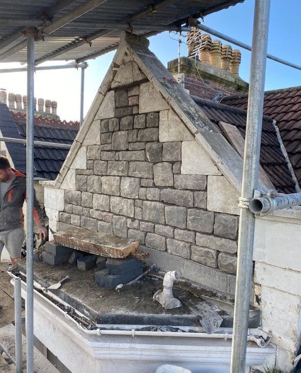 A man is working on a stone wall on the side of a building.