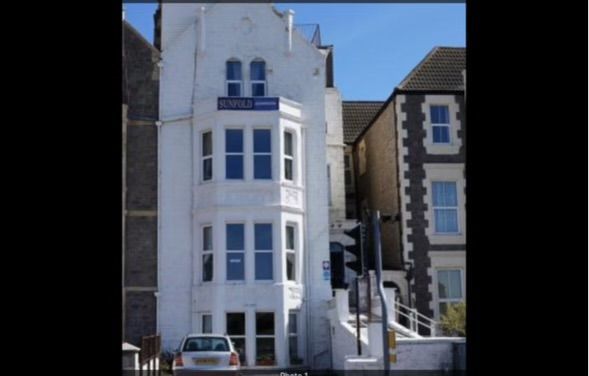 A white car is parked in front of a tall white building