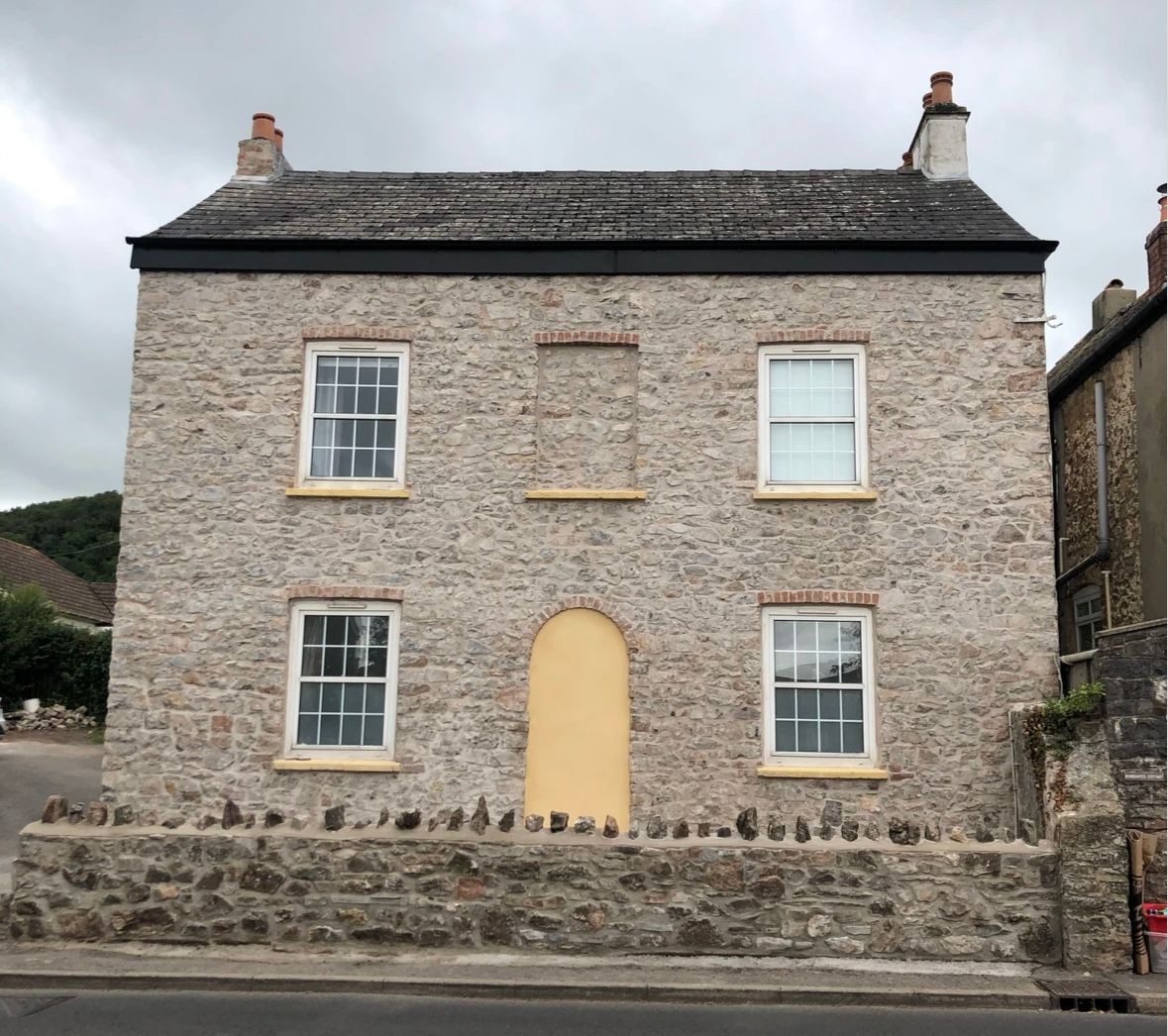 A large stone building with a yellow door and windows