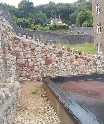 A stone wall with a brick building in the background