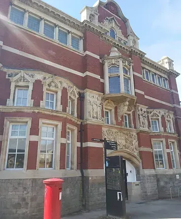 A large brick building with a red post box in front of it