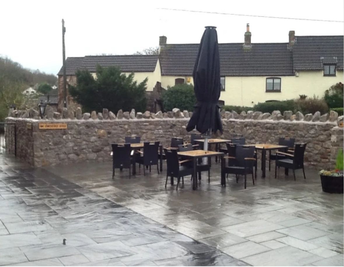 A patio with tables and chairs and umbrellas on a rainy day