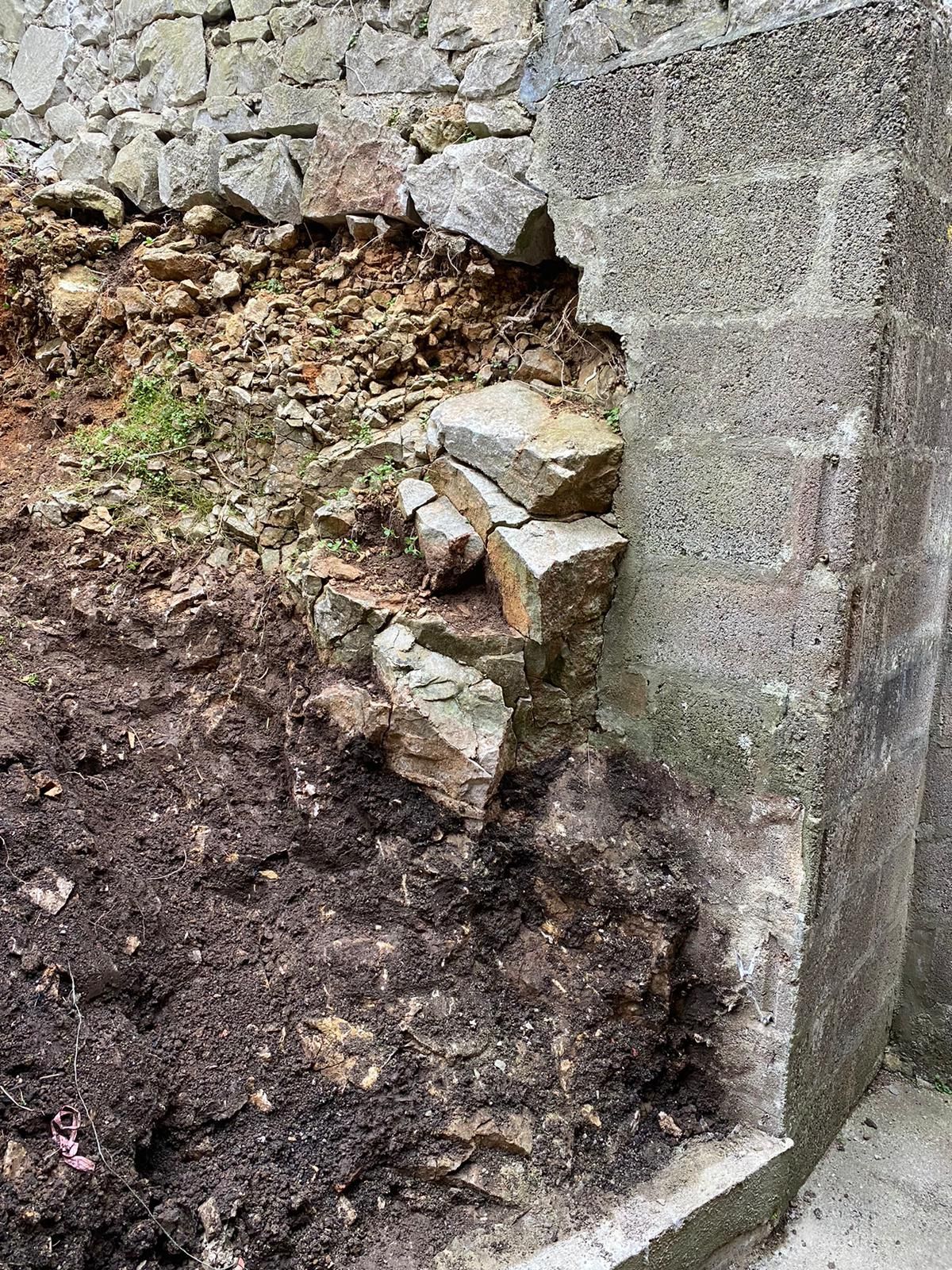 A pile of dirt and rocks next to a brick wall.