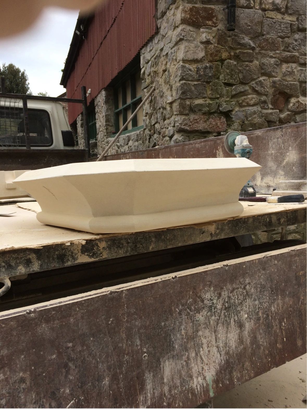 A white bowl is sitting on a wooden table in front of a brick building.