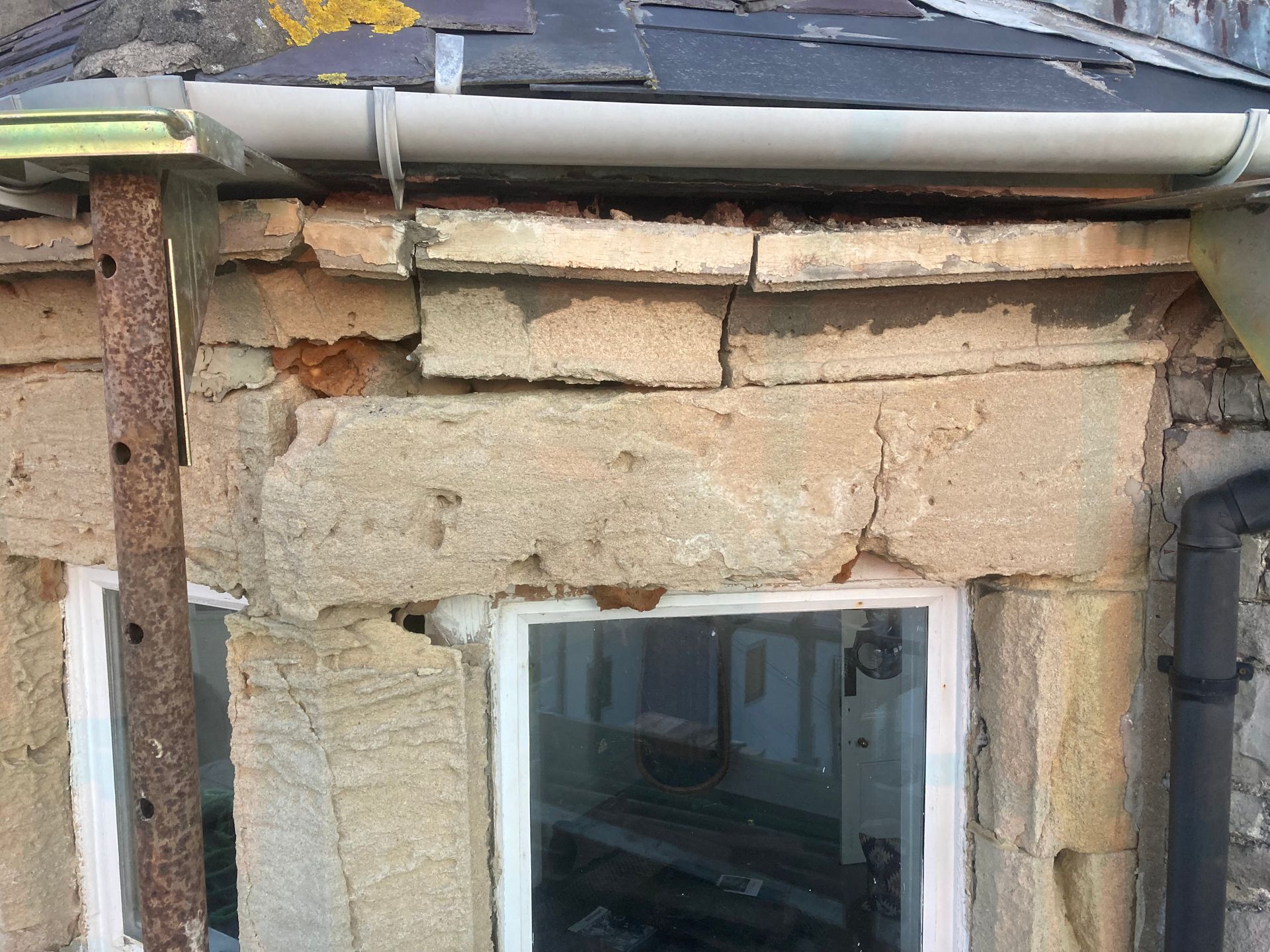 A brick wall with a window and a gutter on it