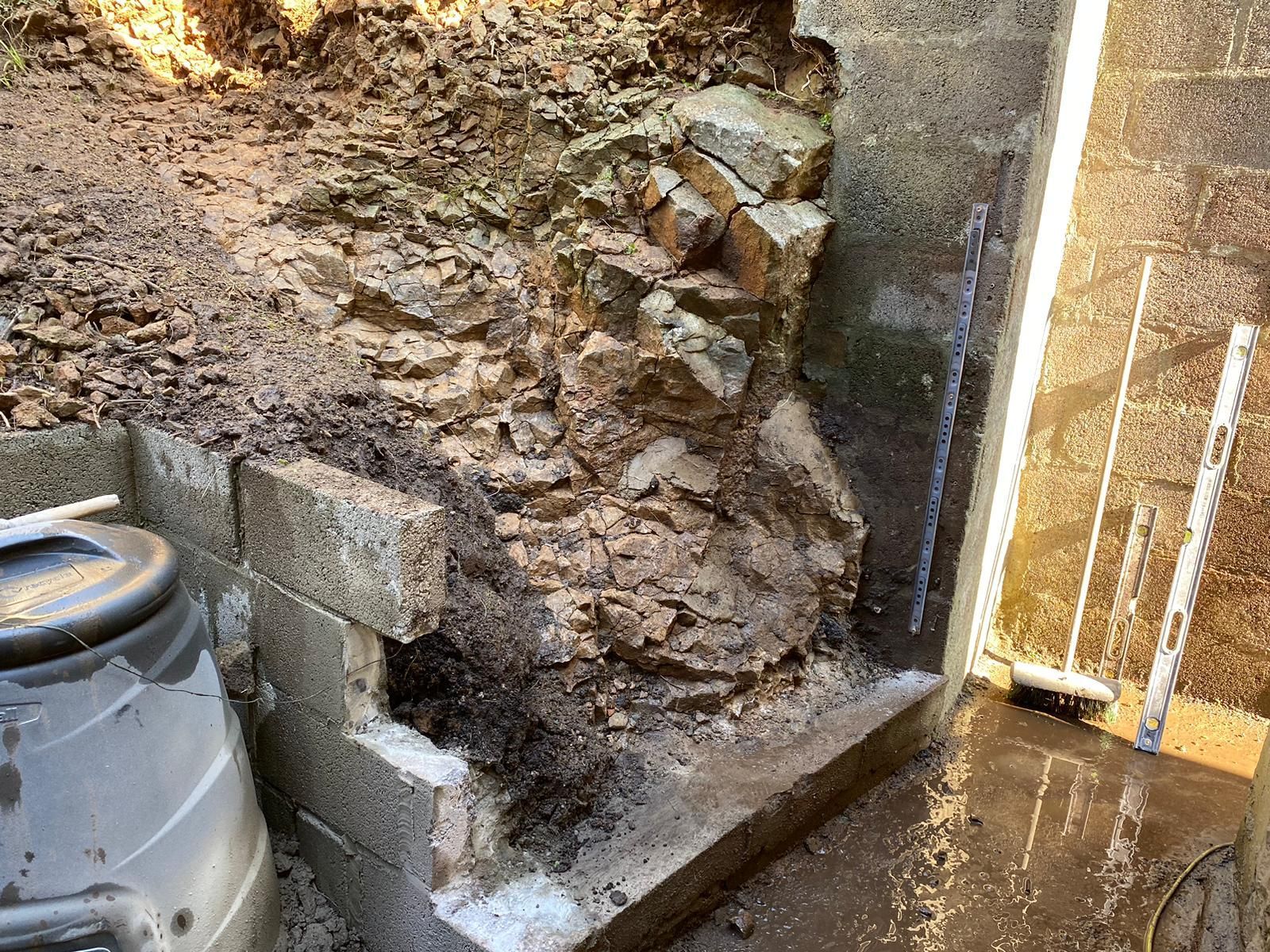 A trash can is sitting next to a pile of rocks.