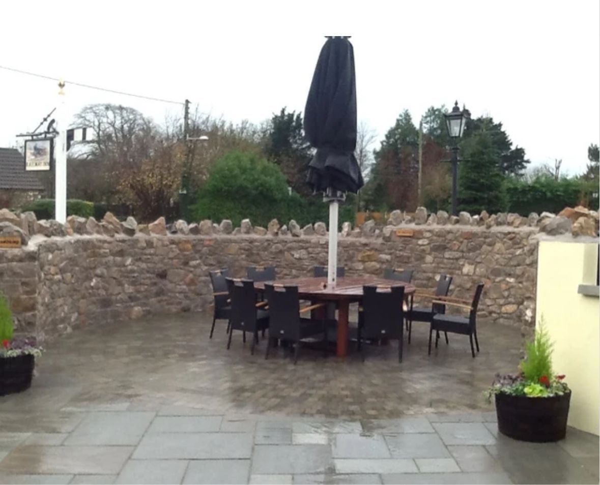 A patio with a table and chairs and a black umbrella