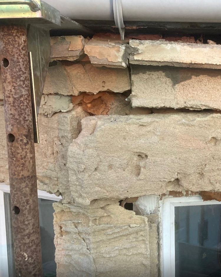 A close up of a brick wall with a window in the background.