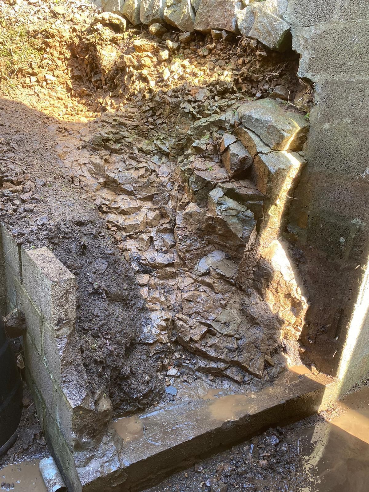 A pile of rocks is sitting on the ground next to a wall.