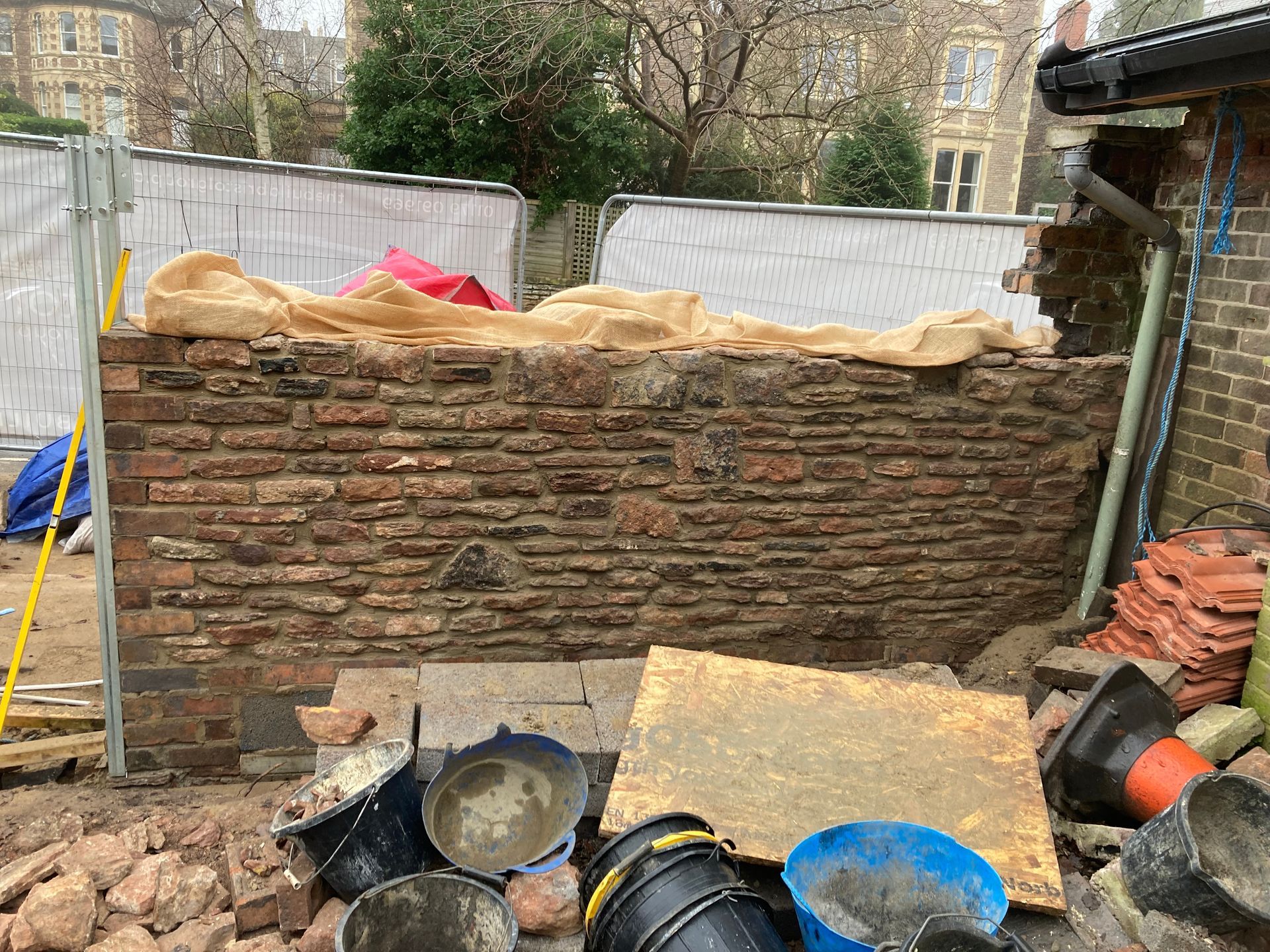 A brick wall is being built next to a pile of buckets.