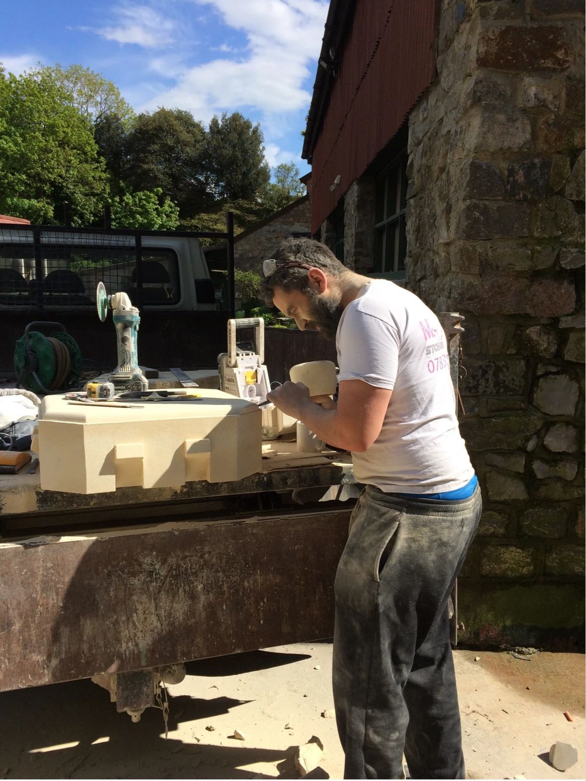 A man in a white shirt is working on a piece of stone