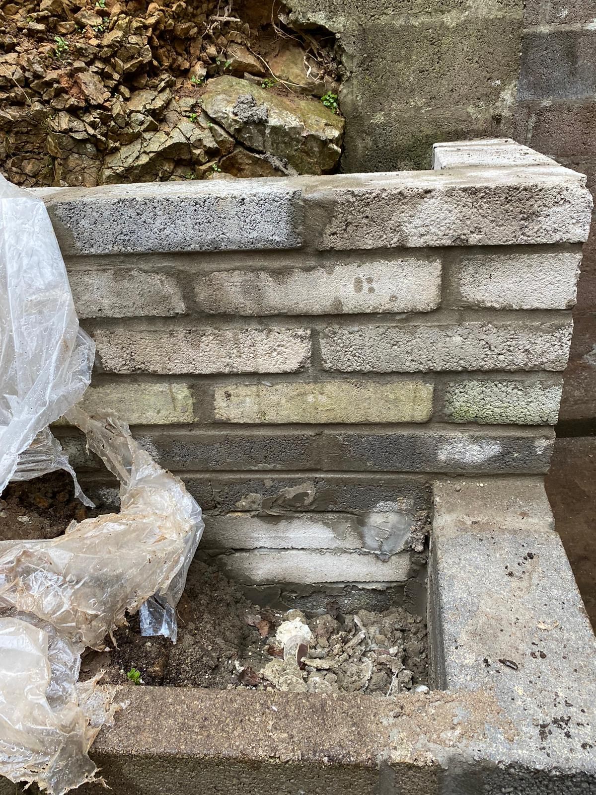 A brick wall is being built next to a pile of leaves.
