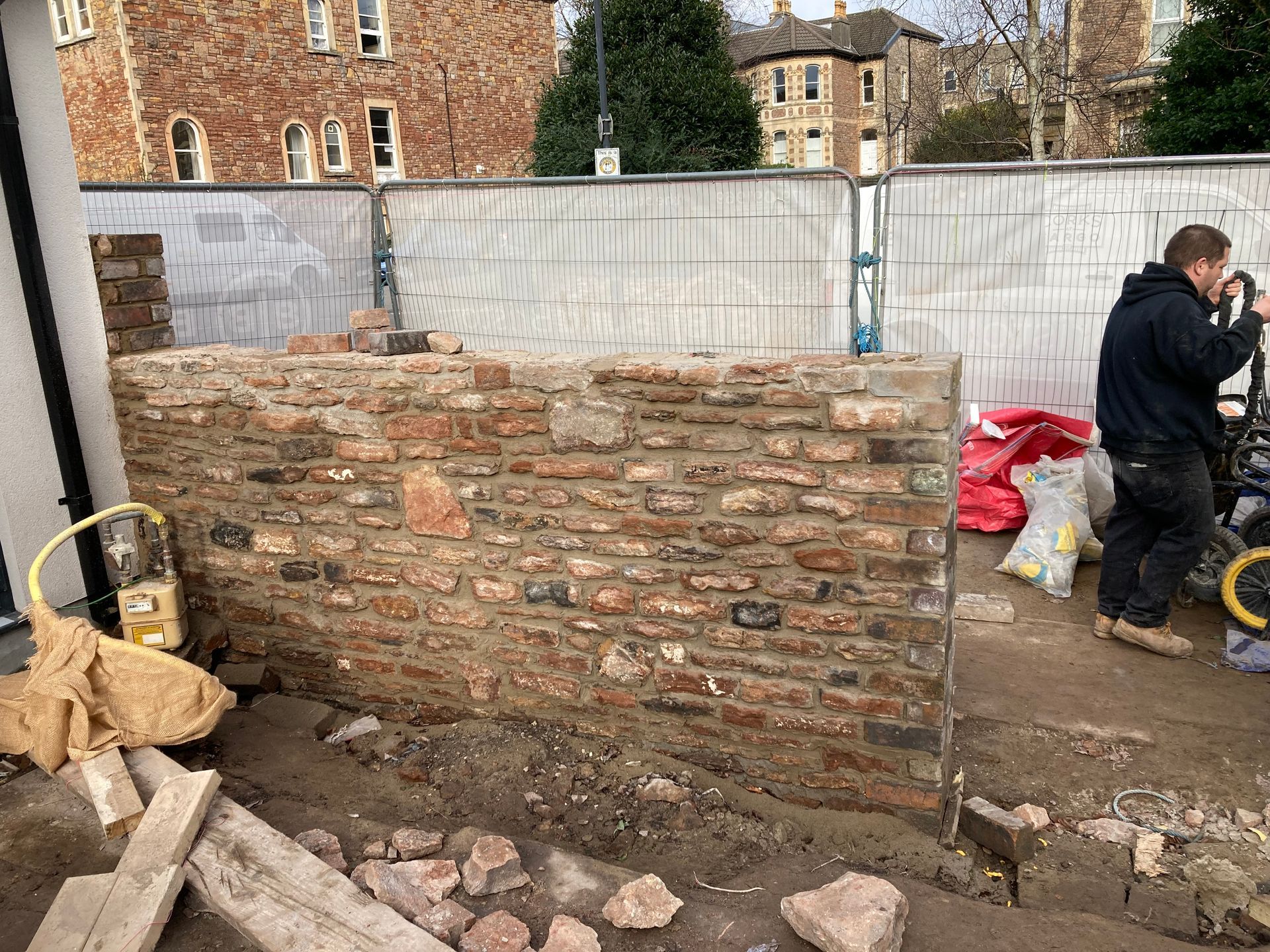 A man is standing in front of a brick wall.