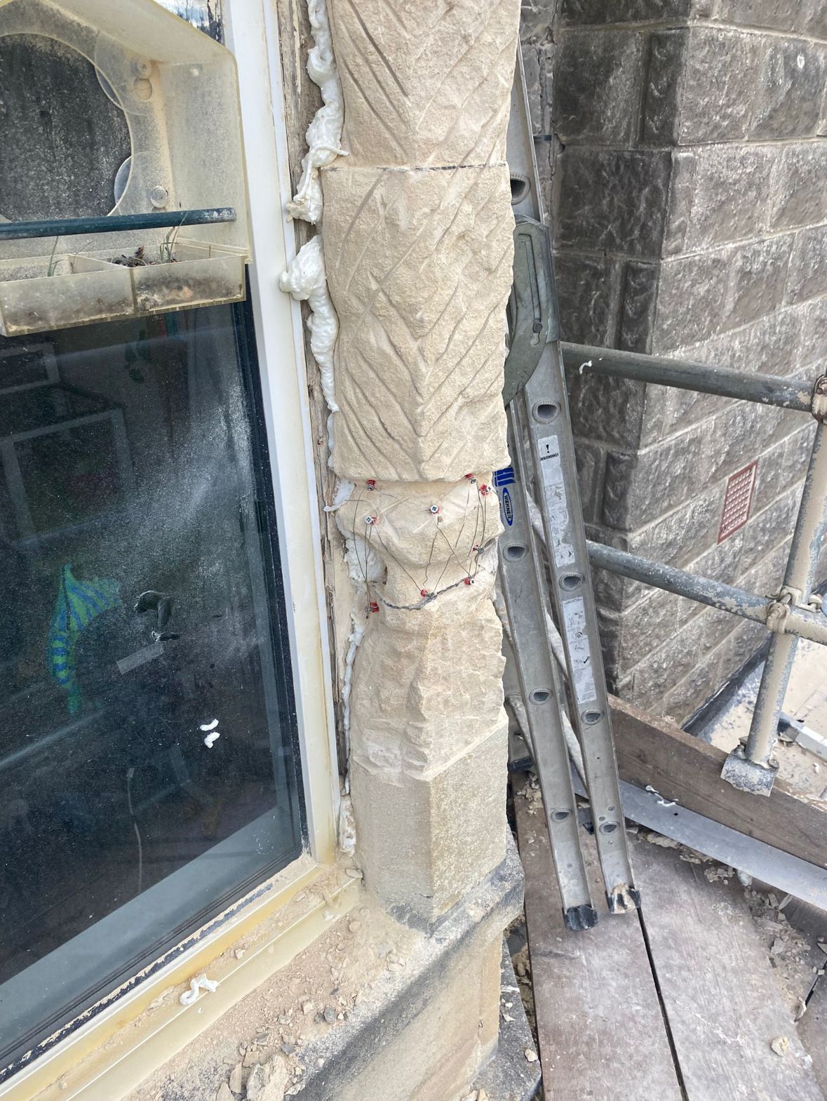 A ladder is sitting next to a window on the side of a building.