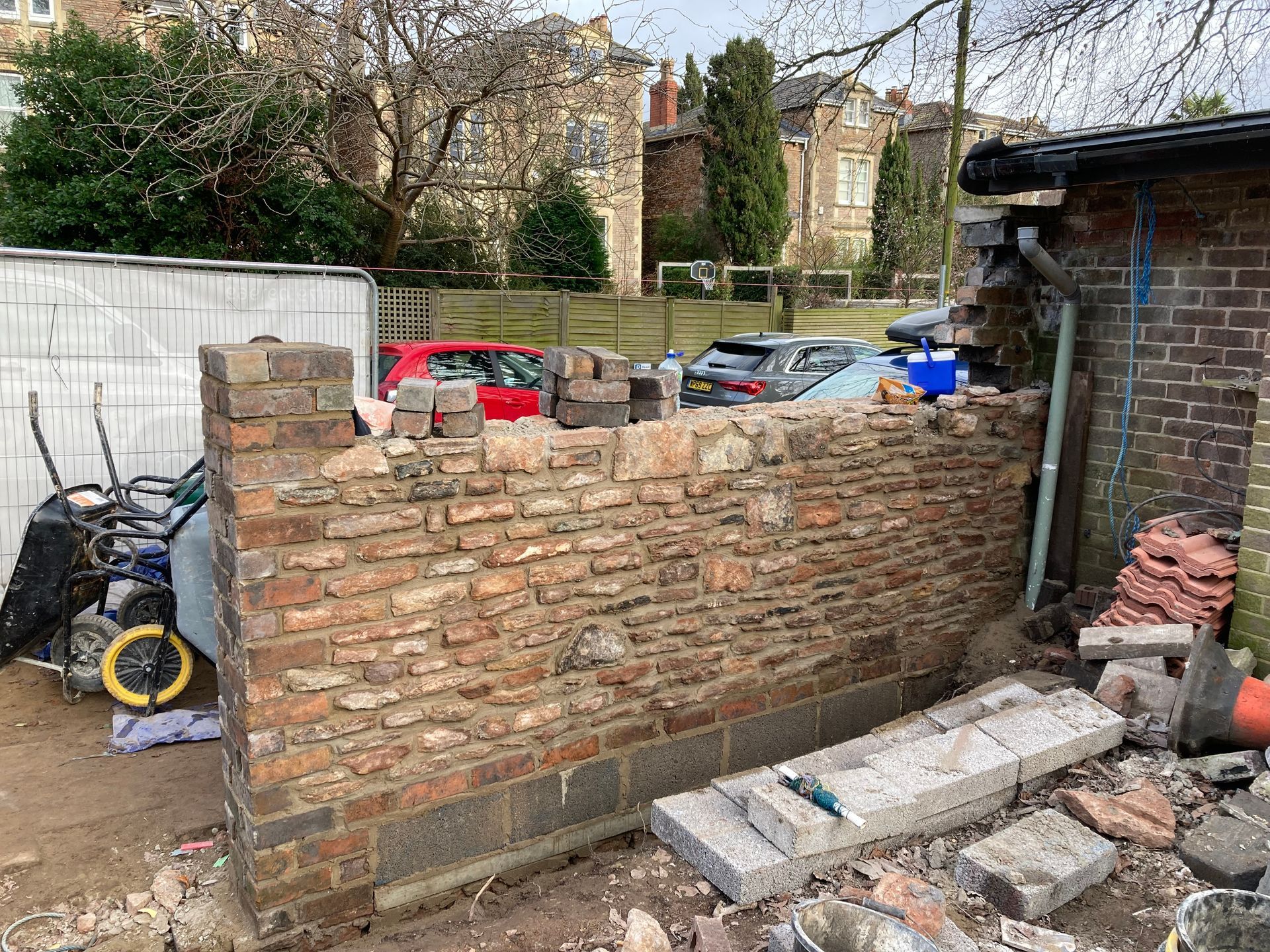 A brick wall is being built next to a shed.