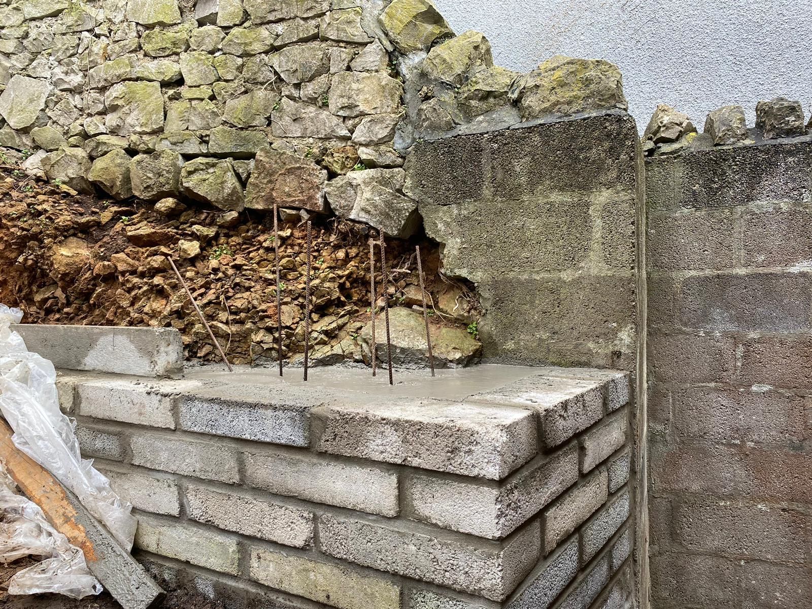 A brick wall is being built next to a pile of rocks.