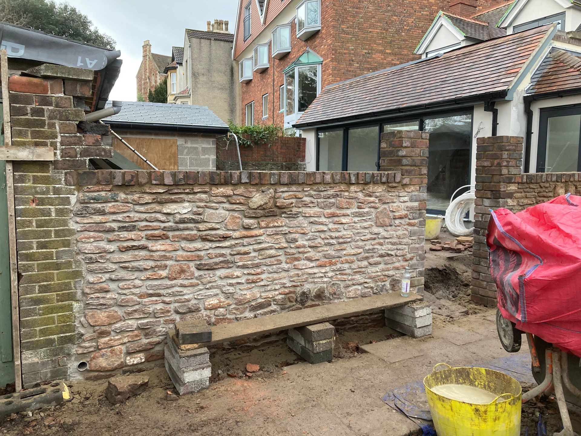 A brick wall is being built in the backyard of a house.