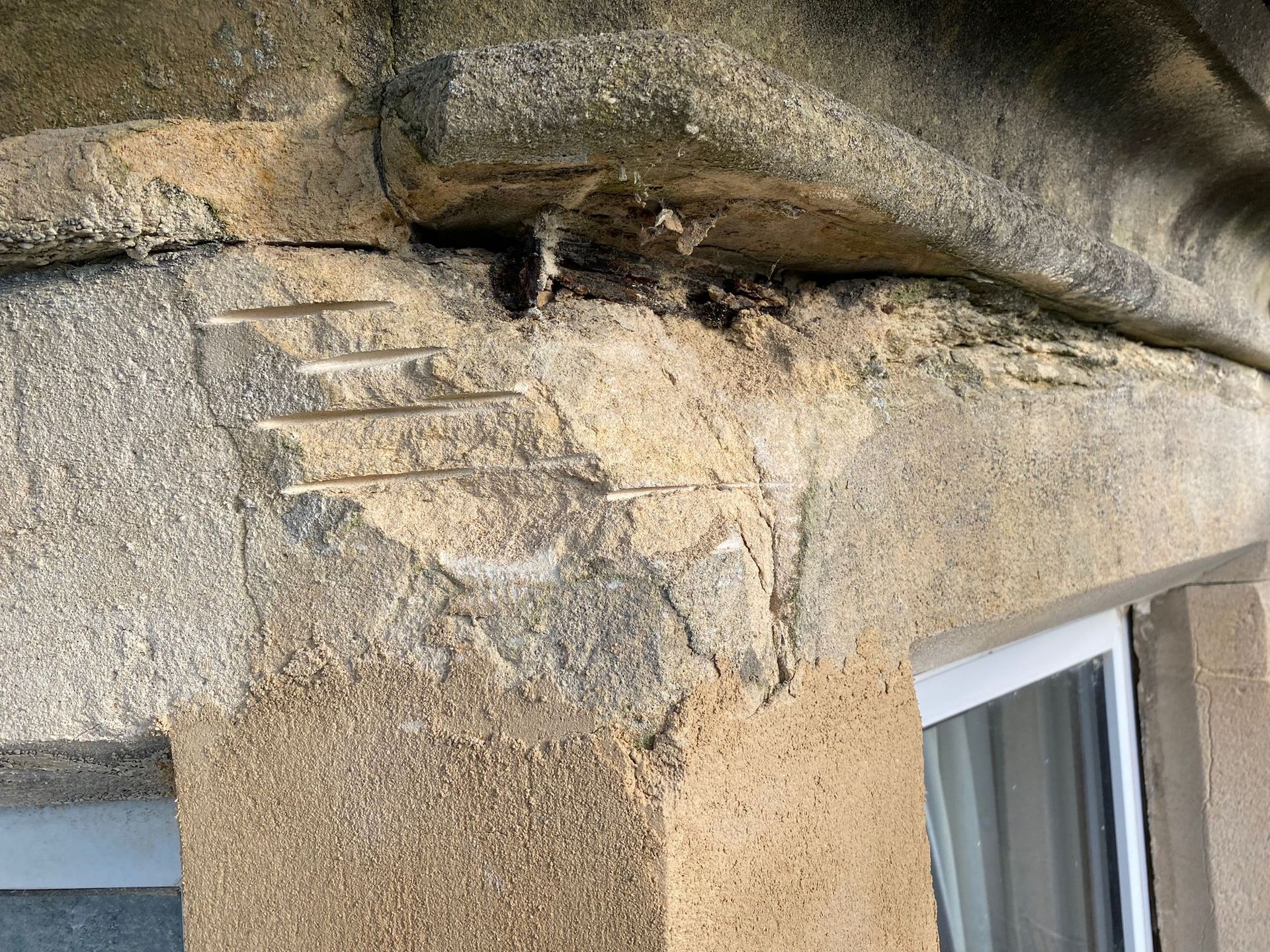 A close up of a concrete wall with a window in the background.