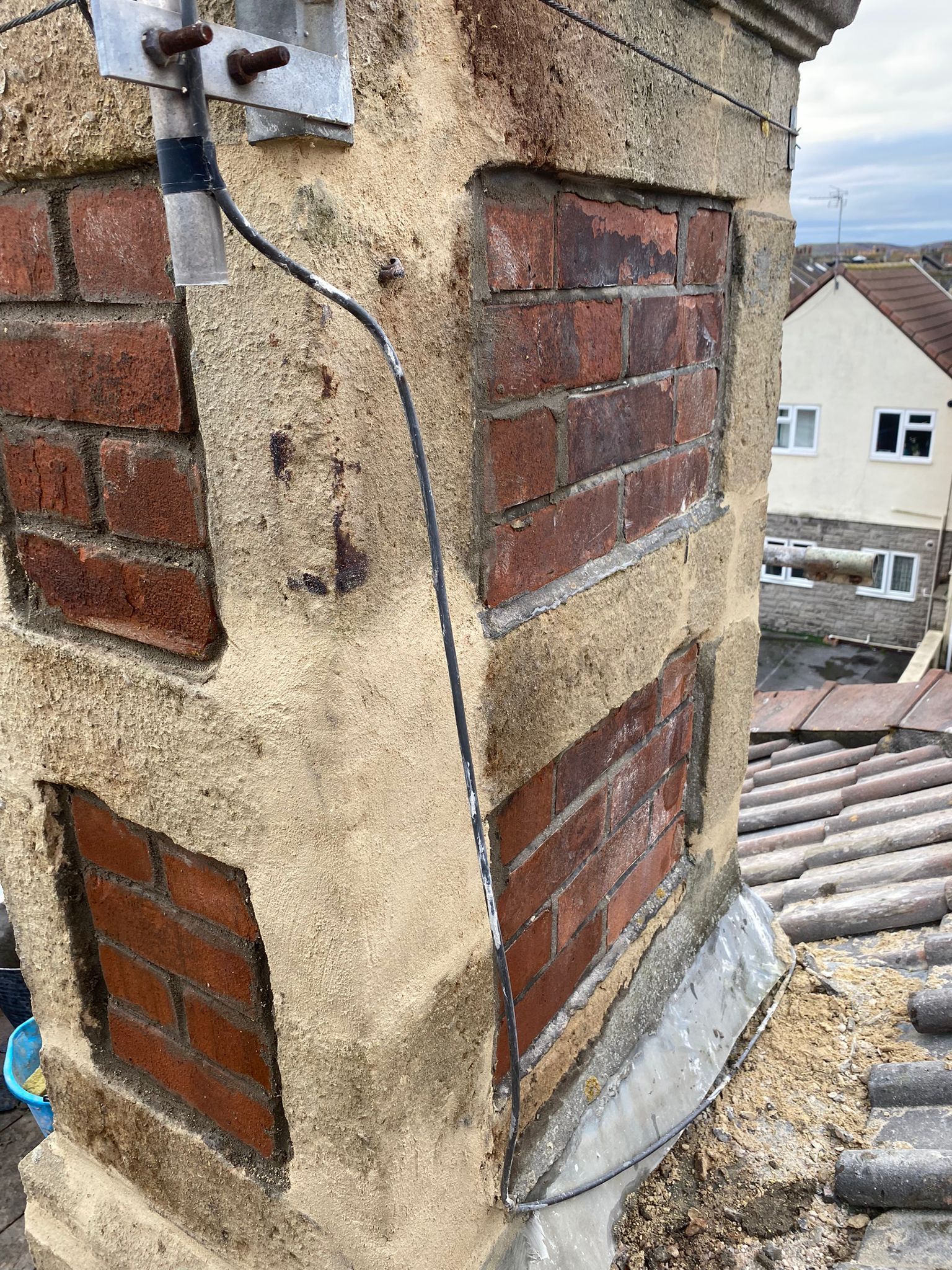 A brick chimney on top of a roof with a cable coming out of it.