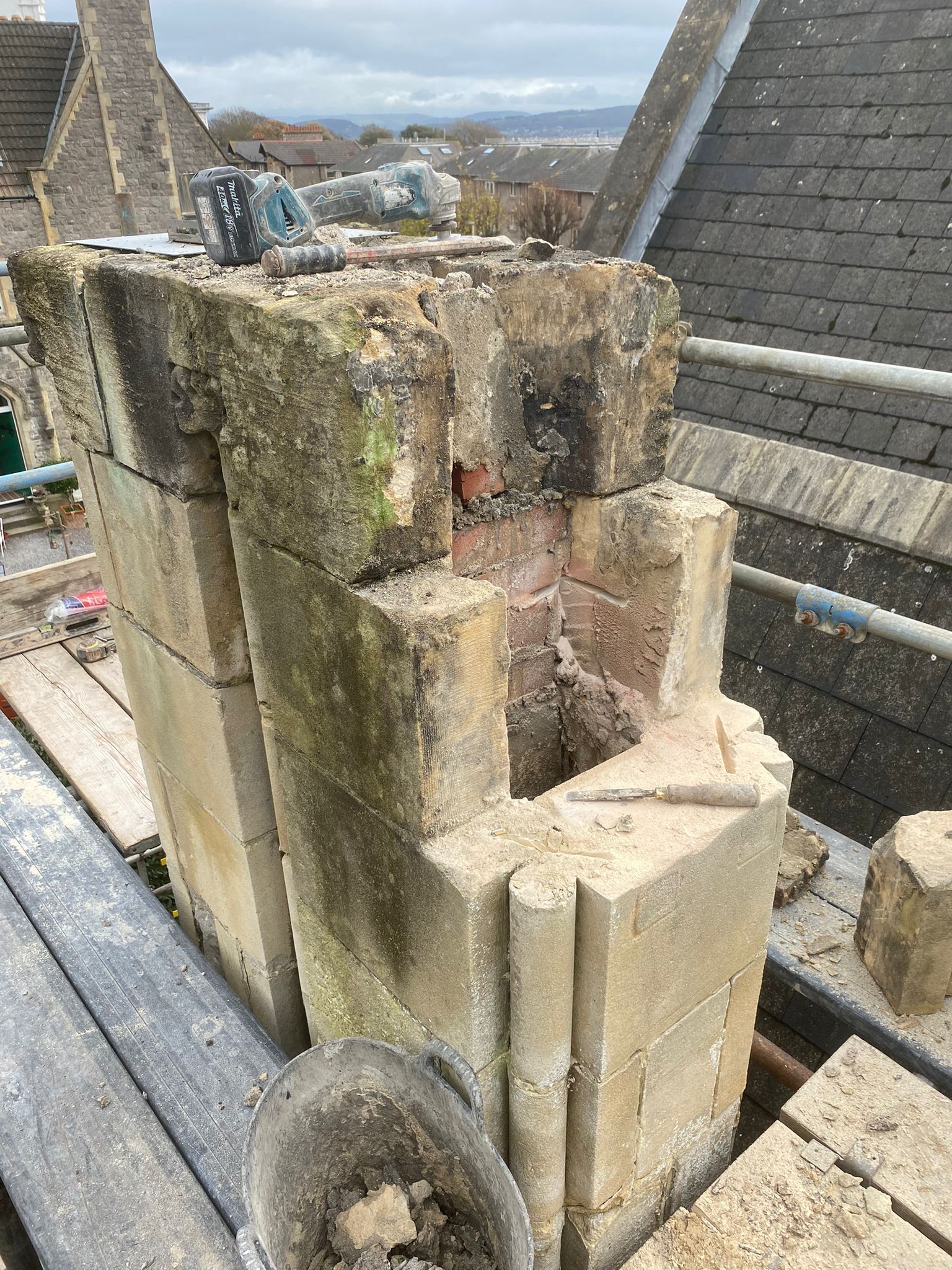 A stone chimney is sitting on top of a wooden scaffolding.
