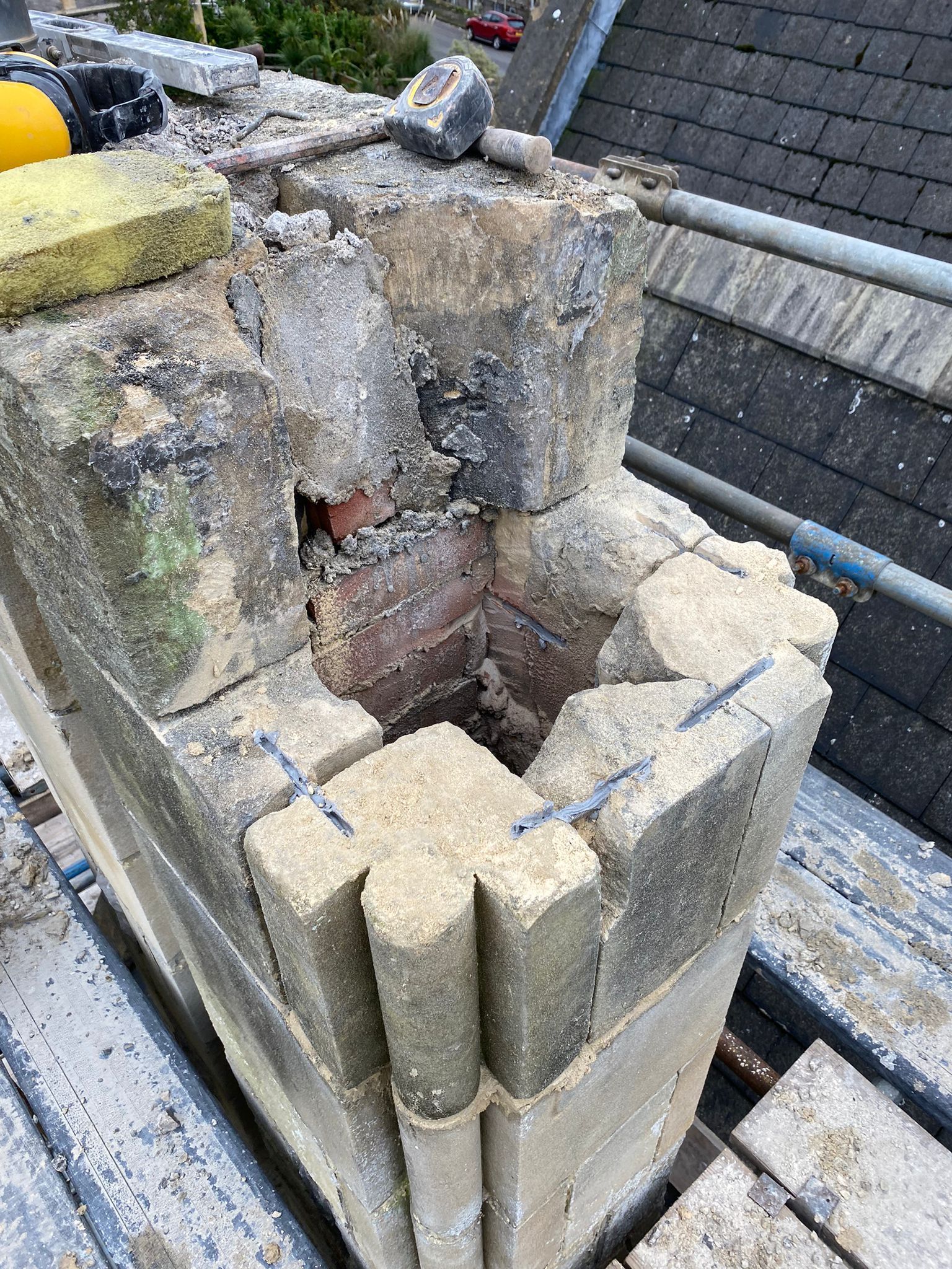 A brick chimney is being repaired on the roof of a building.