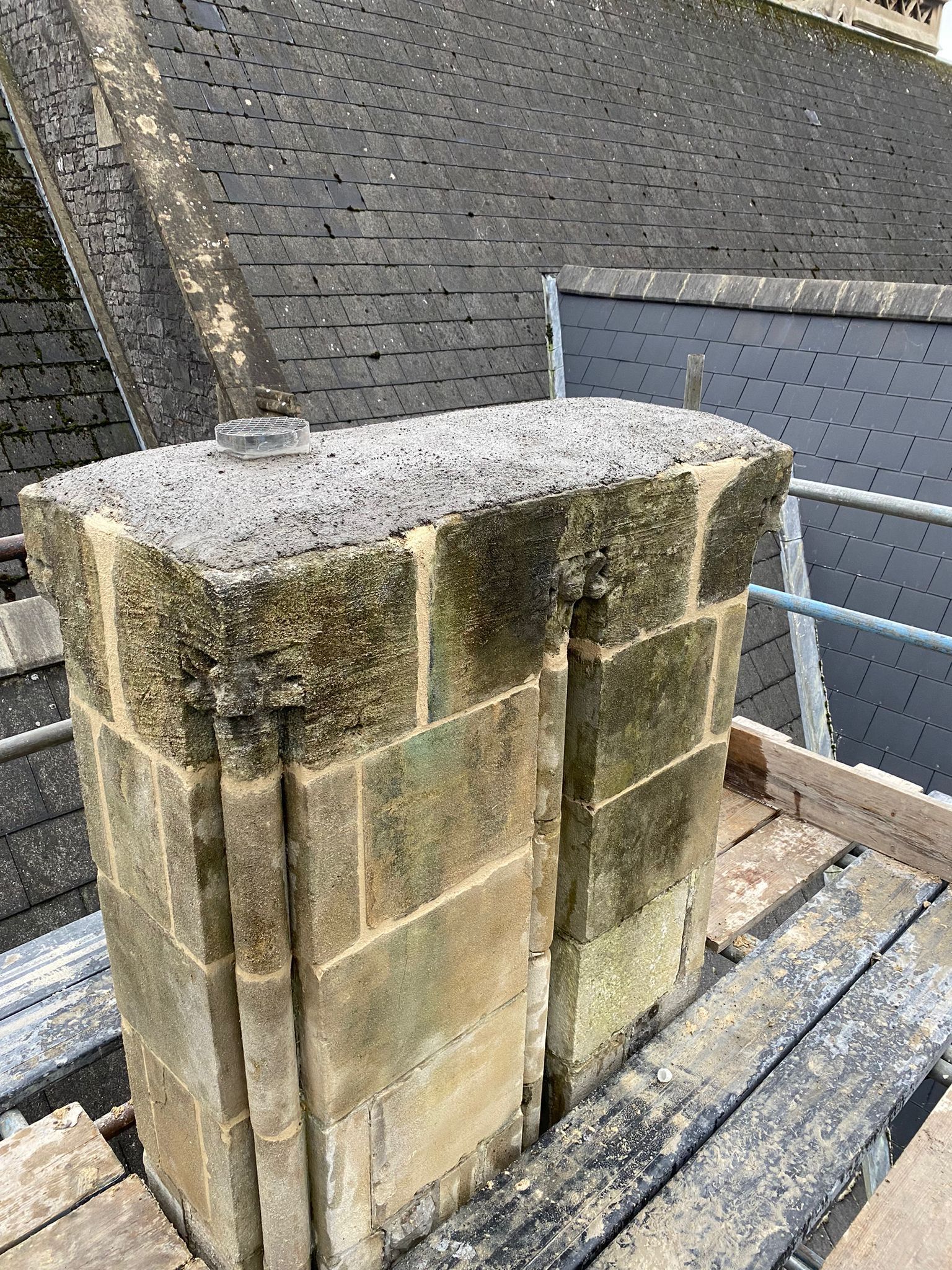 A chimney is sitting on top of a wooden scaffolding on the roof of a building.