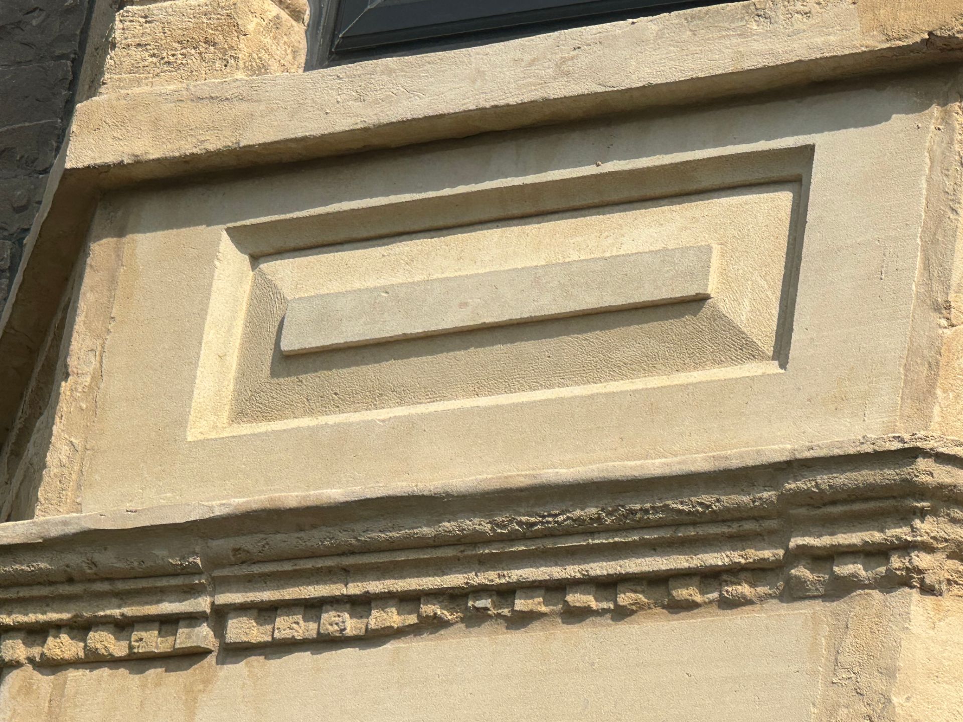 A close up of a stone wall with a window in the background