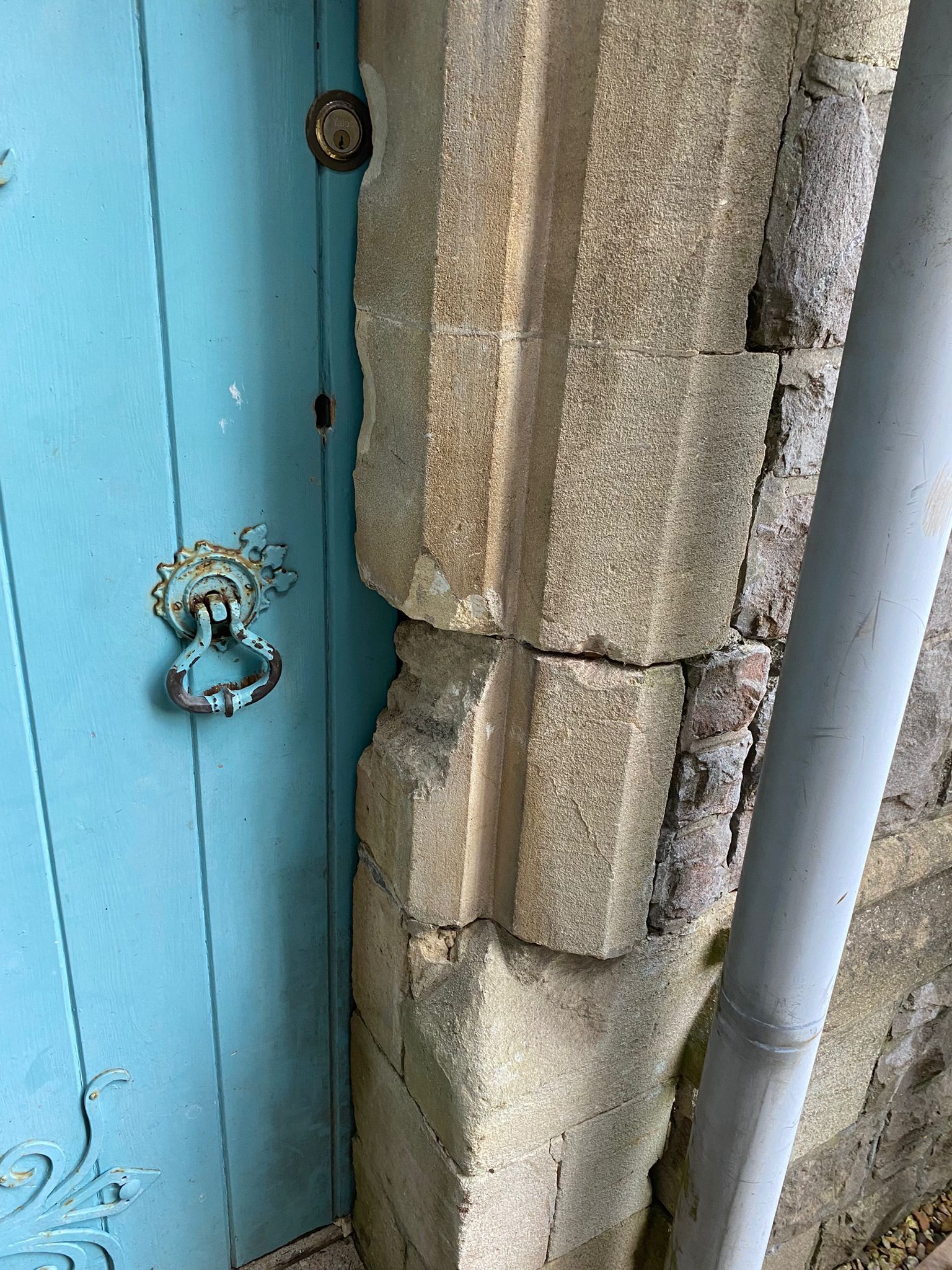 A blue door is sitting next to a stone wall.