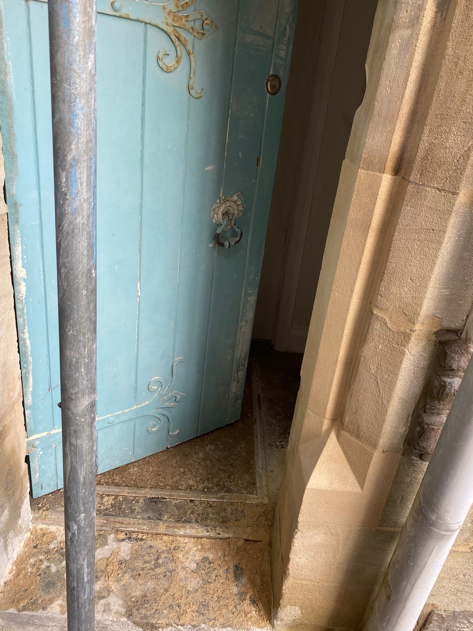 A blue door is open in a building with stairs leading up to it.