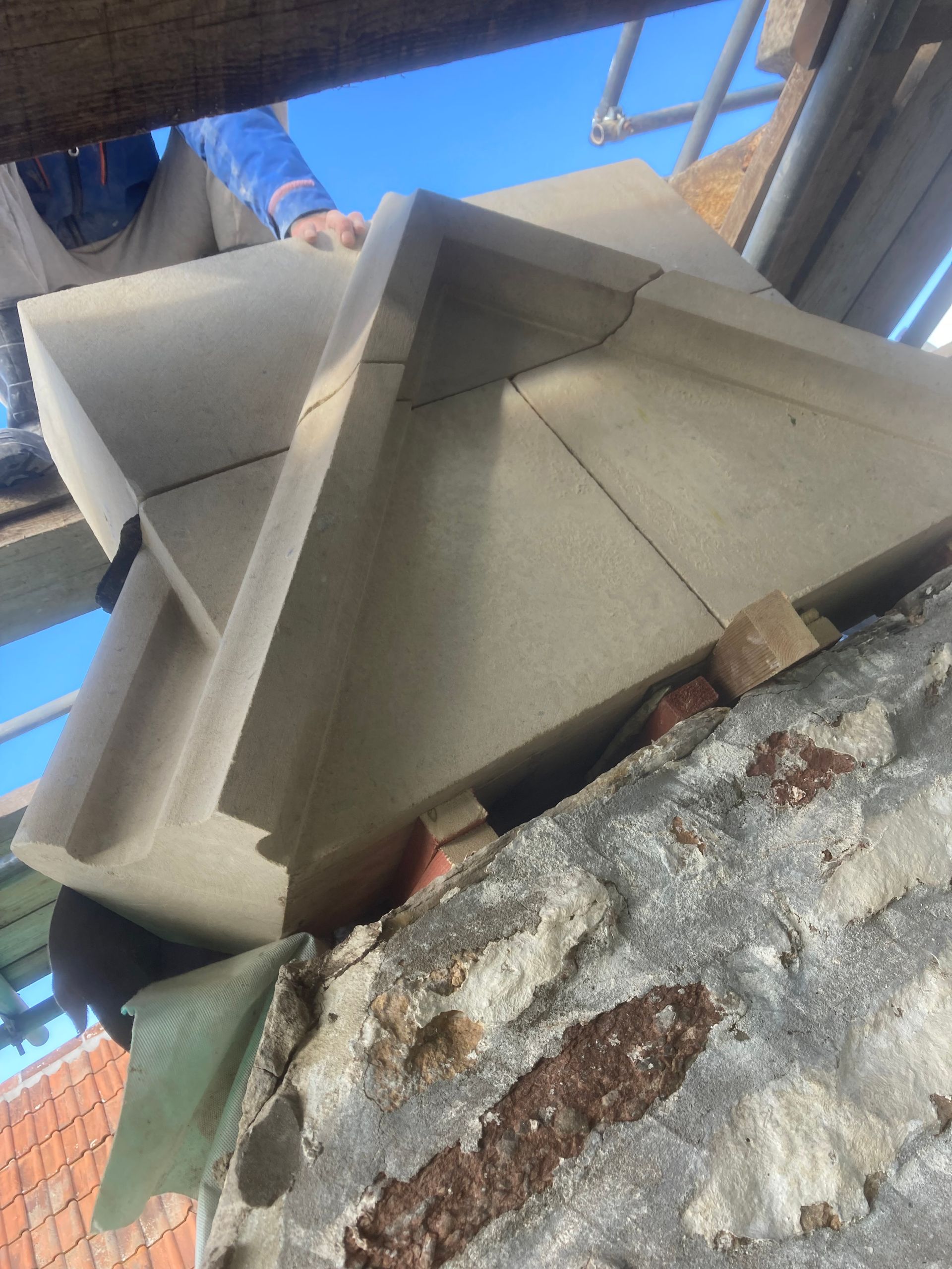 A person is standing on a scaffolding looking up at a pyramid shaped structure.