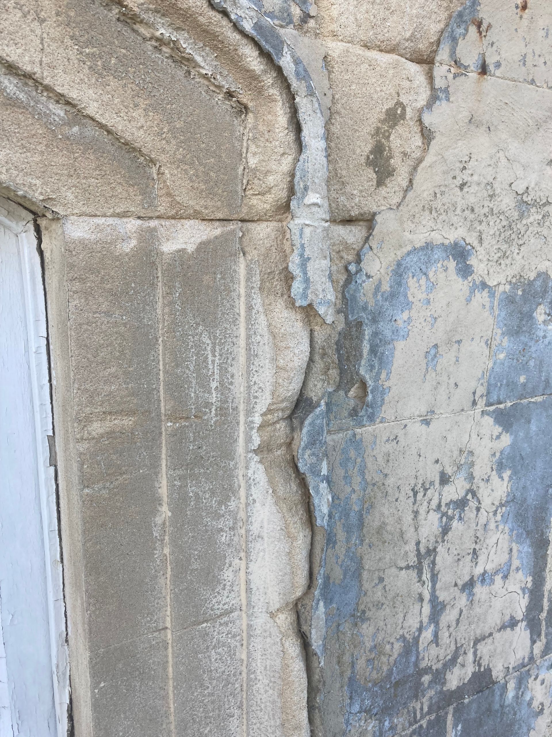 A close up of a stone wall with a window in the background.