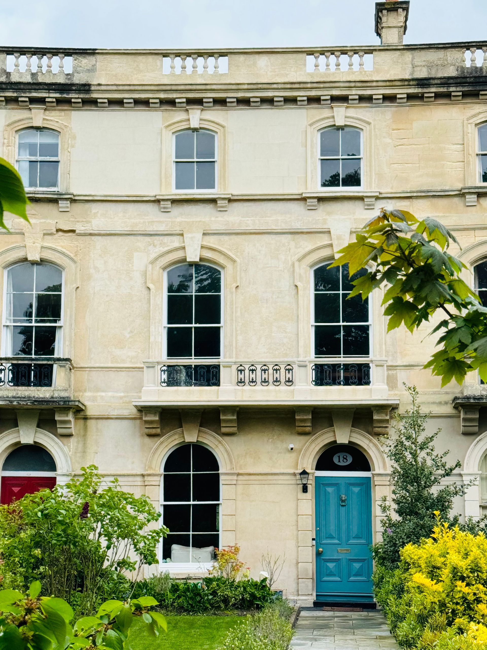 A large white building with a blue door and balcony