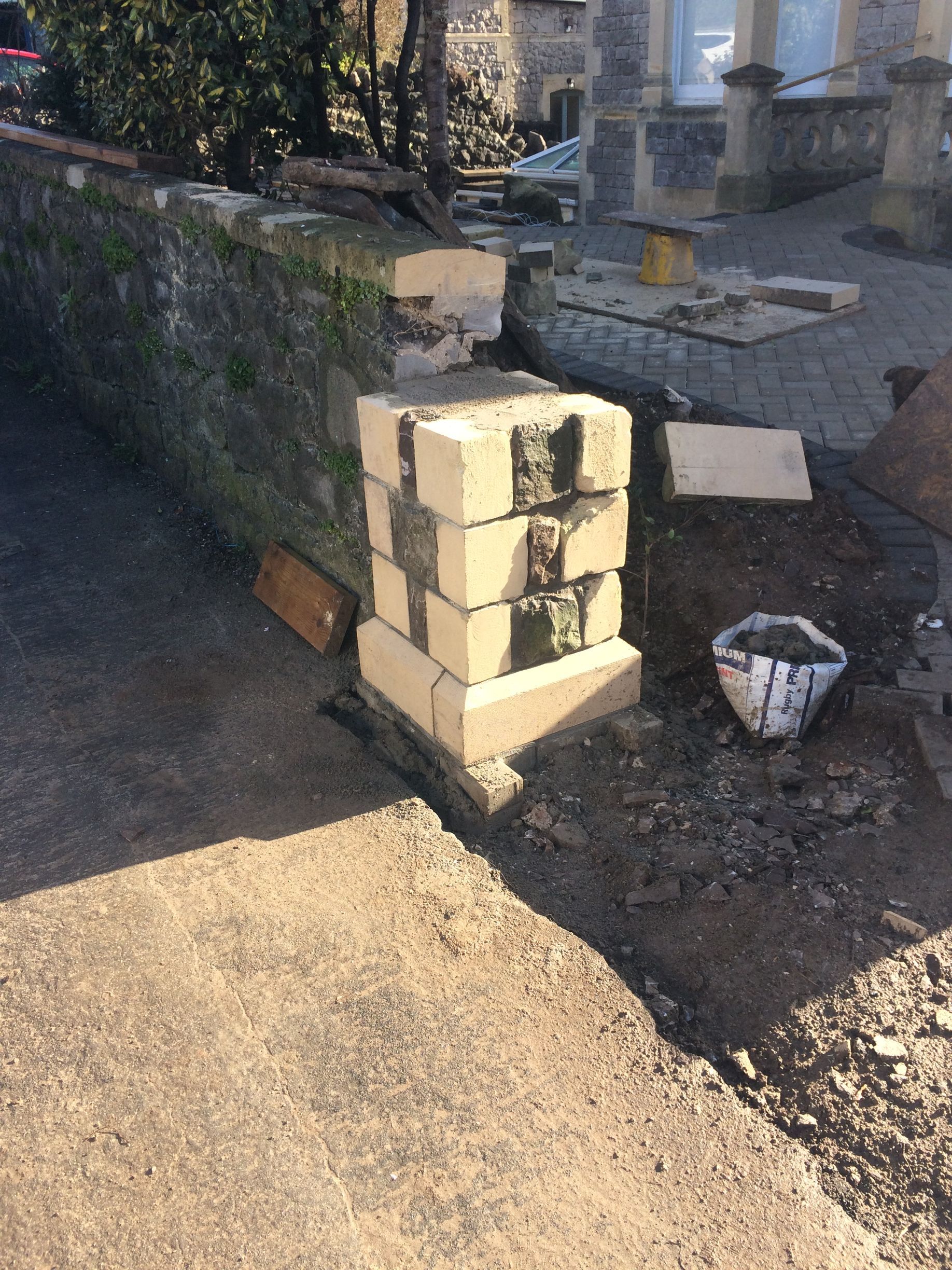 A stack of bricks is sitting on the ground next to a wall.