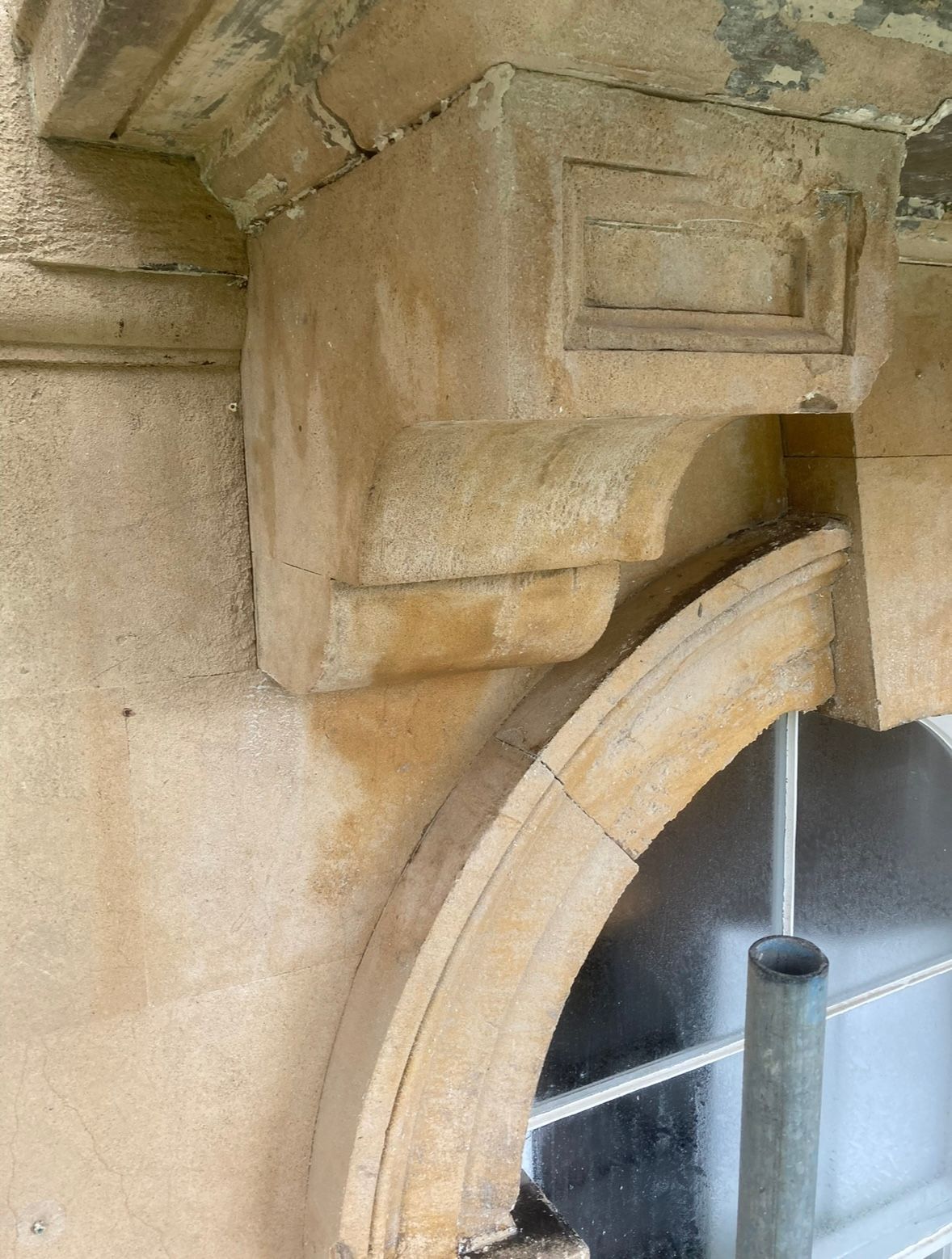 A close up of a stone arch on a building with a window.