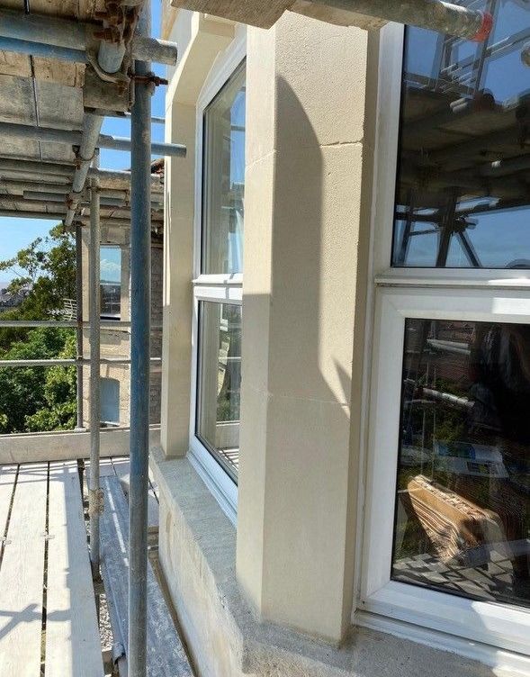 A white window is sitting on a scaffolding on the side of a building.