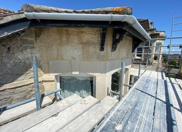 A scaffolding is sitting on top of a building next to a window.