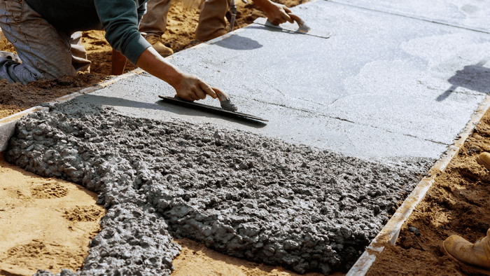 Concrete contractors shaping a concrete sidewalk. 