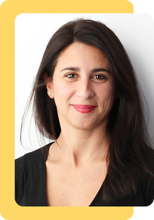 Una mujer de pelo largo y oscuro sonríe y lleva una camisa negra.